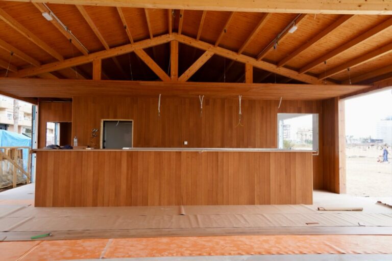Wooden bar counter under construction inside a timber structure with exposed ceiling beams.