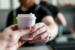 Persona recibiendo un café caliente en un establecimiento