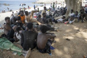 Grupo de migrantes en la playa de Ceuta esperando asistencia