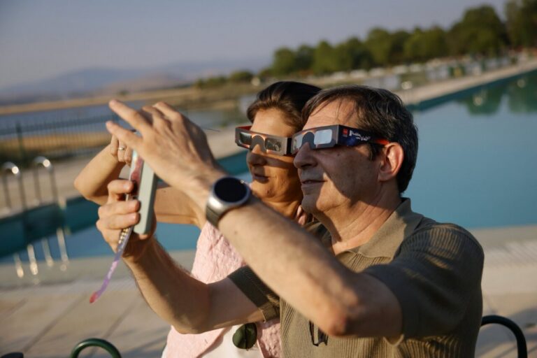 Pareja usando gafas de eclipse mientras observan el fenómeno astronómico