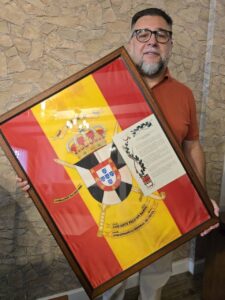 Hombre sosteniendo una bandera histórica enmarcada de la Comandancia de Ceuta