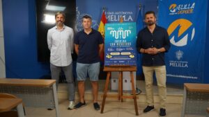 Tres hombres posando junto a un cartel del programa Entrena con Nosotros en Melilla