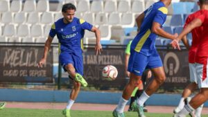 Jugador de fútbol entrenando en el campo con balón en Melilla