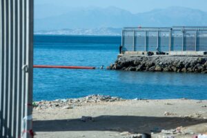 Vista del mar y la frontera en Ceuta con un hombre cerca del agua