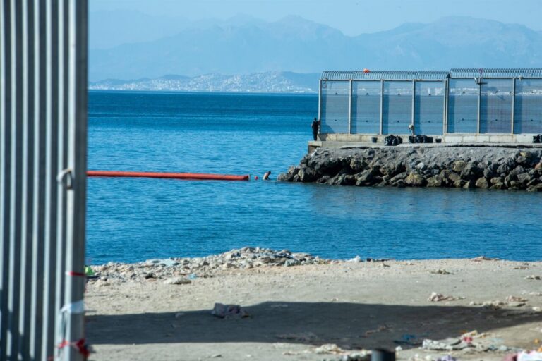 Vista del mar y la frontera en Ceuta con un hombre cerca del agua