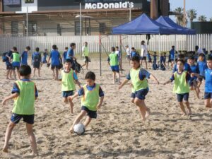 Niños jugando al fútbol en la playa durante la escuela de fútbol