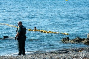 Agente de seguridad observa a un joven en el agua cerca de la playa