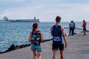 Personas caminando por el puerto de Melilla junto al mar