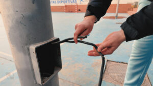 Persona revisando un cable eléctrico en una instalación pública