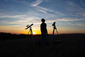 Persona observando un eclipse solar con telescopios al atardecer