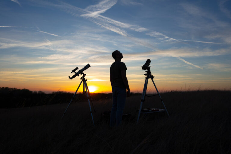 Persona observando un eclipse solar con telescopios al atardecer
