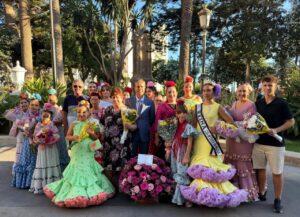 Grupo de personas en trajes tradicionales con flores en la ofrenda floral