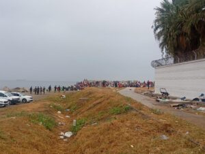 Grupo de inmigrantes en la playa El Trampolín con presencia policial.