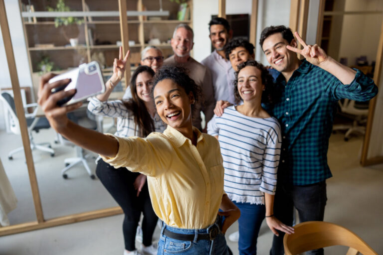 Grupo de personas sonriendo mientras toman una selfie en la oficina