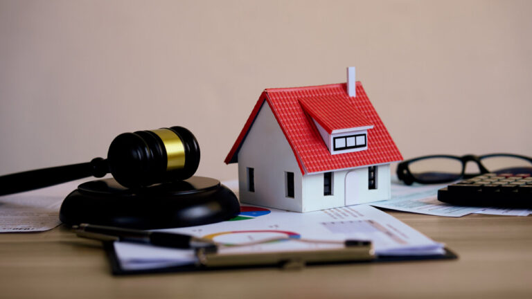 Maqueta de casa junto a un martillo de juez y documentos legales