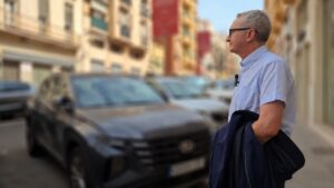 Hombre de pie en la calle observando coches aparcados