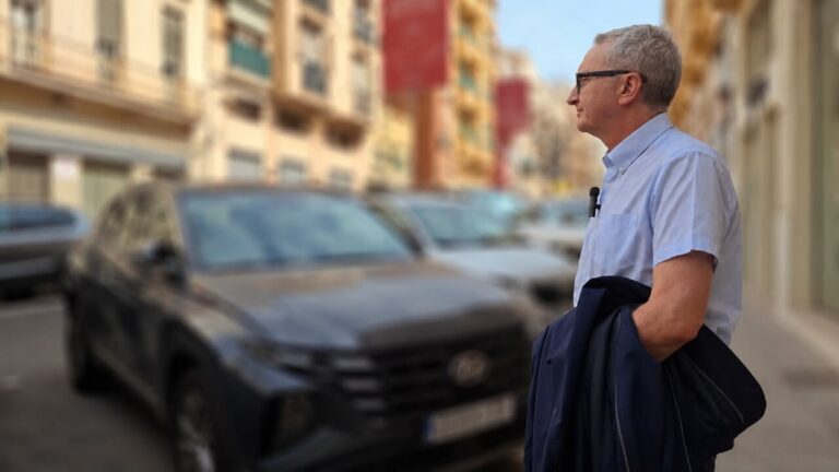 Hombre de pie en la calle observando coches aparcados