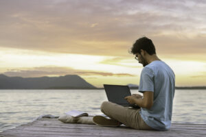 Hombre trabajando en un portátil al atardecer junto al mar
