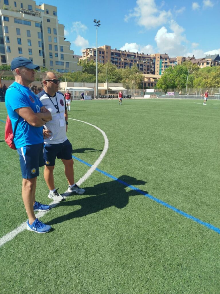 Dos entrenadores observan un partido de fútbol en un campo de Melilla.