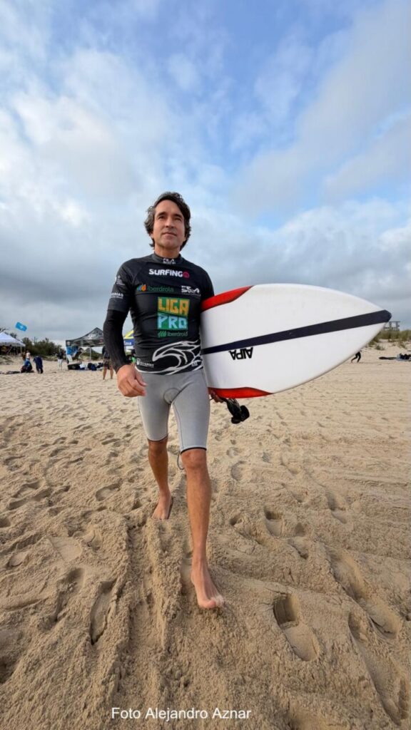 Competidor de surf en la playa con una tabla de surf en la mano