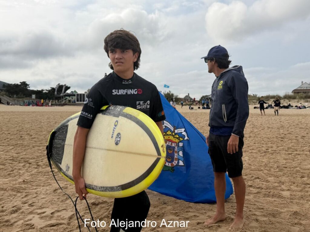 Joven surfista con tabla en la playa durante el campeonato de surf en Melilla.