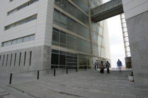 Exterior de la Audiencia de Málaga con personas entrando y saliendo.