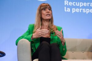 Begoña Gómez hablando durante un evento con fondo azul