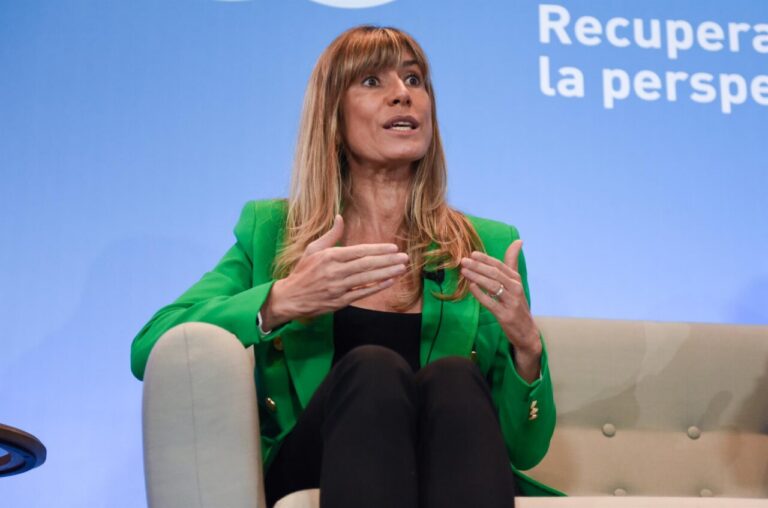 Begoña Gómez hablando durante un evento con fondo azul