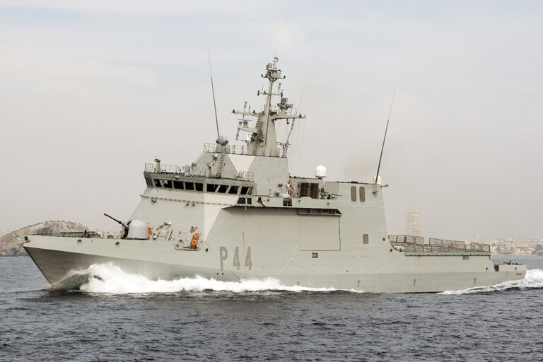 Gray naval destroyer at sea, bow cutting through waves, hull marked R44. (informative)
