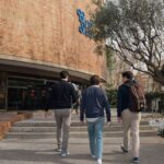 Estudiantes caminando hacia un colegio mayor en un campus universitario