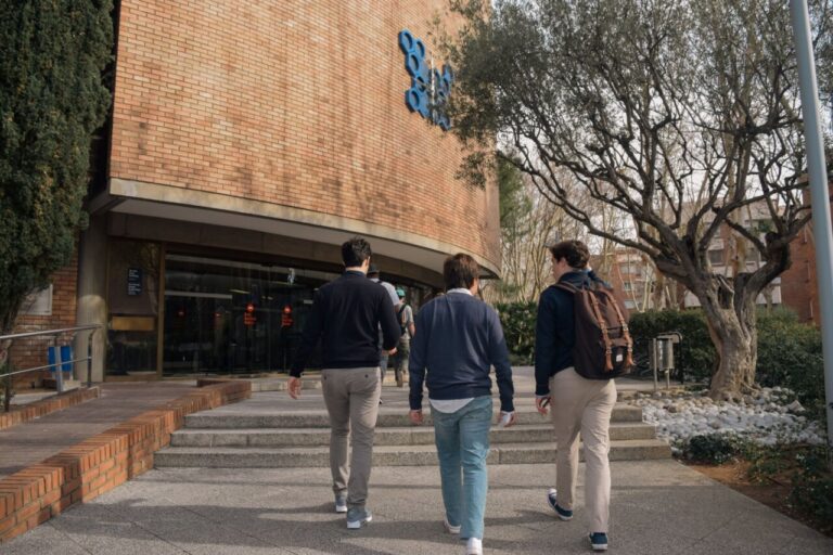 Estudiantes caminando hacia un colegio mayor en un campus universitario