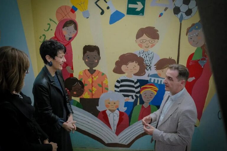Elma Saiz conversando en Melilla con un mural colorido de fondo
