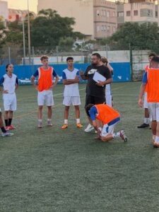 Cristian Carmona dirigiendo un entrenamiento del Atlético Melilla con jugadores en el campo.