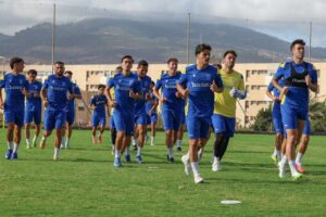 Jugadores de la U.D. Melilla entrenando en el campo con camisetas azules