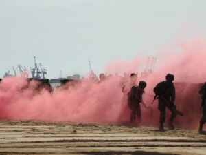 Soldados del Regimiento de Ingenieros en exhibición con humo rosa en la playa.
