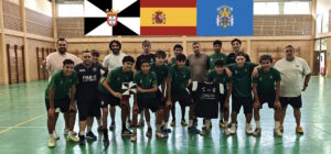 Youth sports team in green uniforms posing for a group photo in an indoor gym, with coaches at either end and flags overhead (including Portugal and Spain).