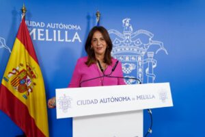 Mujer en conferencia de prensa en Melilla con bandera española