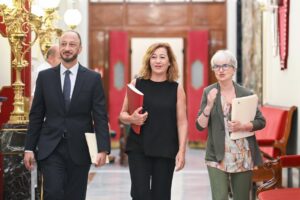Tres personas caminando en el Congreso de España con documentos en mano