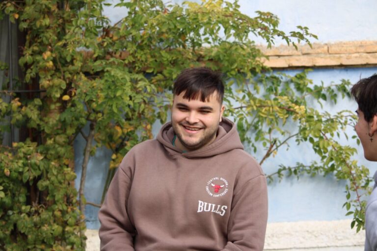 Joven sonriendo en un entorno natural con vegetación