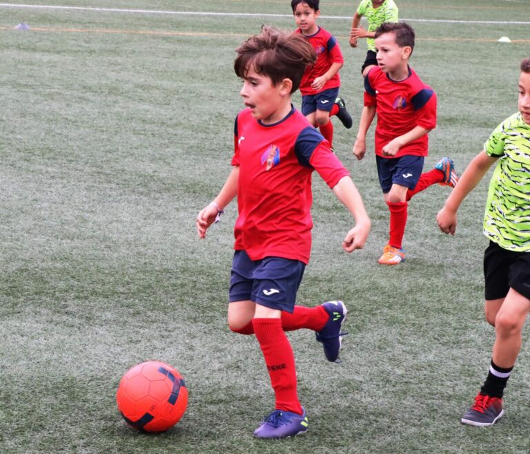 Niños jugando al fútbol en un campo de hierba artificial