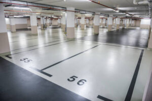 Underground parking garage with empty spaces; foreground shows spots 55 and 56 marked on the light floor.