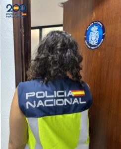Agente de la Policía Nacional en Melilla frente a una puerta con insignia.