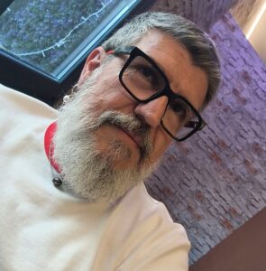 Retrato de un hombre con barba y gafas, reflexionando sobre política y derechos LGTBI.