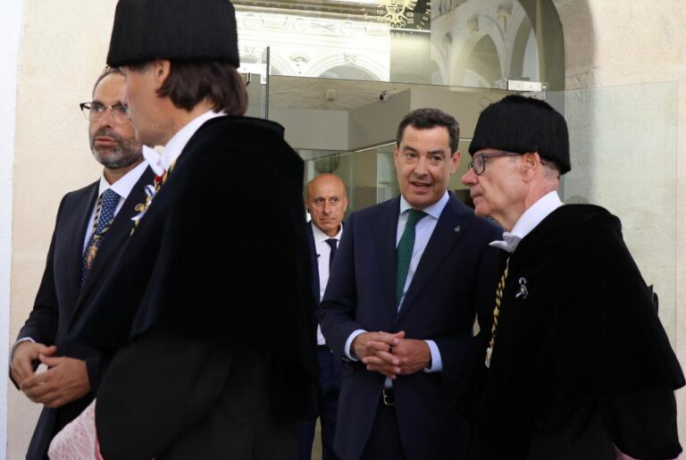 Officials in ceremonial robes and suits converse at an official building entrance.