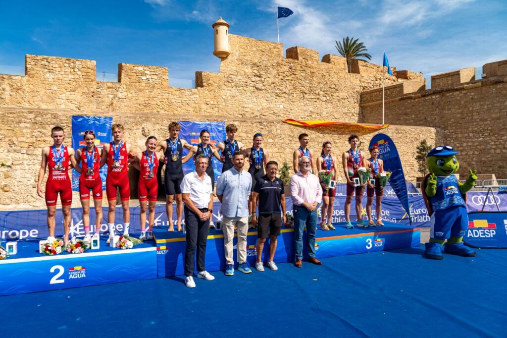 Atletas con medallas posan en un podio durante una ceremonia deportiva al aire libre.