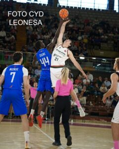 Dos jugadores de baloncesto saltan para alcanzar el balón durante un partido.