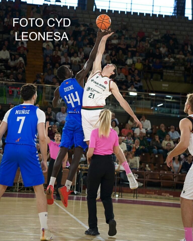 Dos jugadores de baloncesto saltan para alcanzar el balón durante un partido.