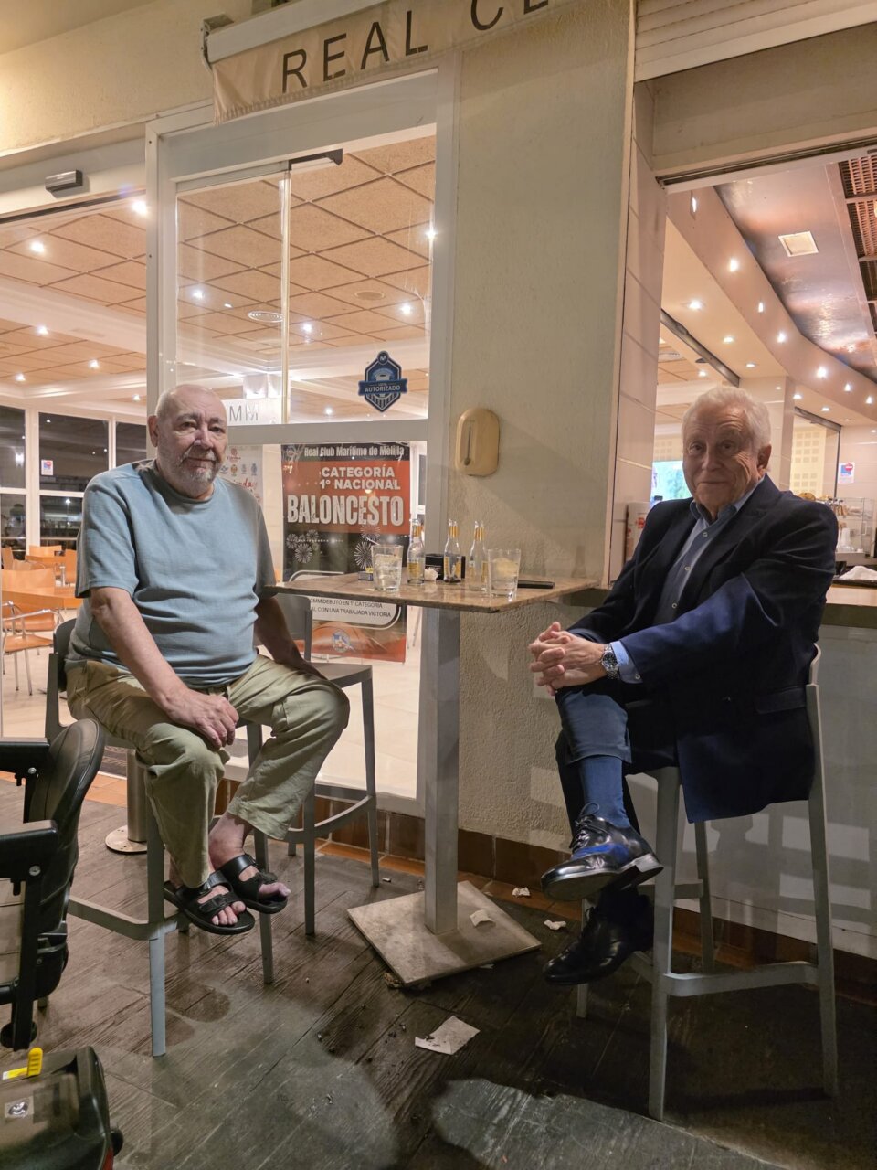 Dos hombres sentados frente a una mesa en el interior de un local