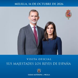 Official poster: a man in a gray suit with burgundy tie and a woman in a navy dress pose formally for a royal visit to Melilla, 14 October 2026; Spanish royal coat of arms top right; blue banner at bottom with the text 'Visita Oficial Sus Majestades los Reyes de España' and 'Ciudad Autónoma de Melilla'.