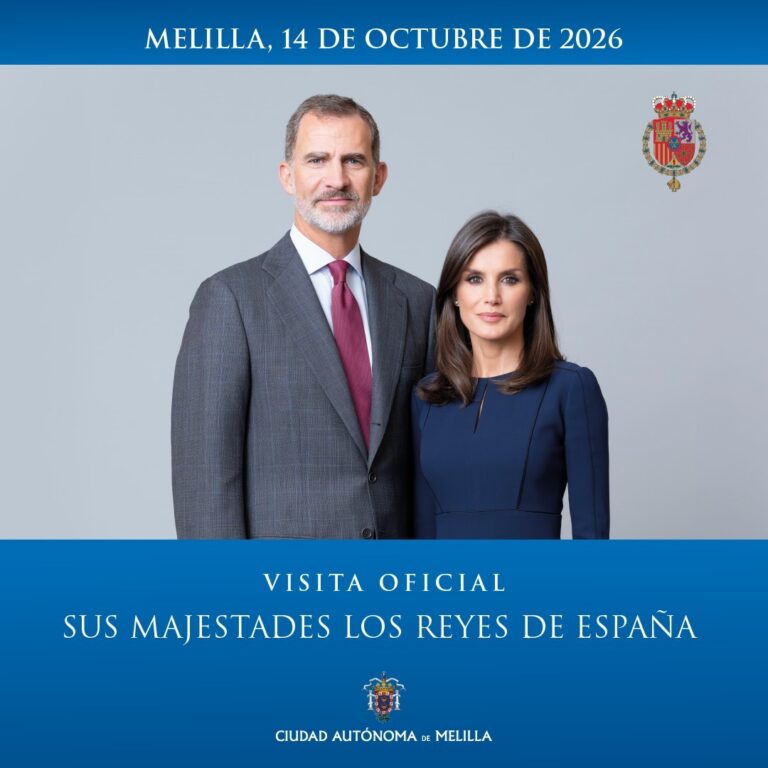 Official poster: a man in a gray suit with burgundy tie and a woman in a navy dress pose formally for a royal visit to Melilla, 14 October 2026; Spanish royal coat of arms top right; blue banner at bottom with the text 'Visita Oficial Sus Majestades los Reyes de España' and 'Ciudad Autónoma de Melilla'.